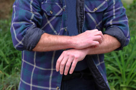Man scratching an itch on his arm