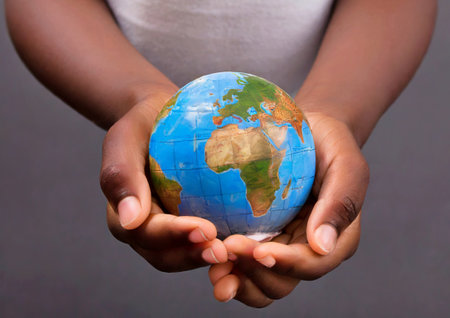 Human hands holding a globe on a dark background. Globalization conceptの素材