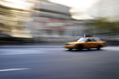 Taxi cab speeding down an urban street in a blur during the daytimeの写真素材