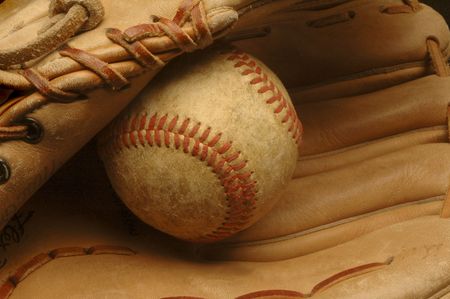A close-up of a well-used baseball nestled in a glove.の写真素材