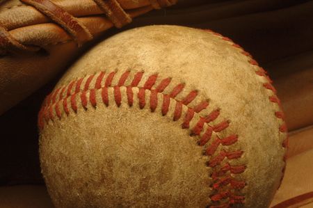 A close-up of a well-worn baseball nestled in a glove.の写真素材