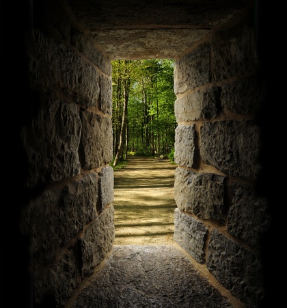 Path through trees as viewed out of a castle-like stone window or passageの写真素材