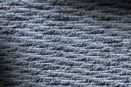 Grooved asphalt or rock surface texture lit diagonally with blue lightの写真素材