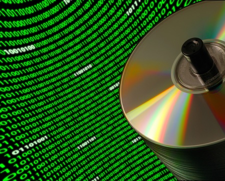 Close-up of a stack of CD/DVD disks on a Dutch angle, with a curved field of binary codeの写真素材