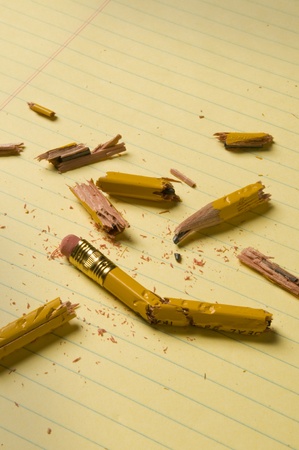 Shattered pencil fragments on a yellow legal pad, perhaps symbolizing writer's blockの写真素材