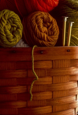 Skeins of wool yarn in a basket with knitting needlesの写真素材