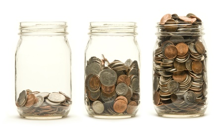 Increasing numbers of American coins in a three glass jars against a white background Increasing numbers of American coins in a three glass jars against a white background