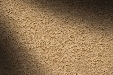 Beige stucco wall texture lit diagonally from leftの写真素材