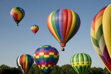 Various hot-air balloons with colorful envelopes ascending or launching at a ballooning festivalの写真素材