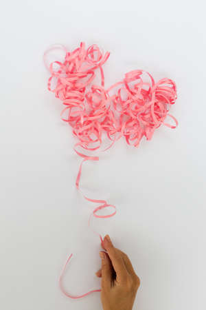 Female hand holding pink ribbon heart. Serpentine heart.の写真素材