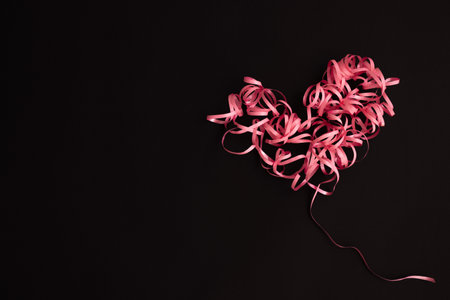 Heart made of ribbon on a black with copy space.の写真素材