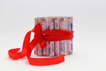 200 gryvnias in a roll with a red gift ribbon. On a white background.の写真素材