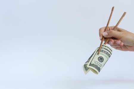 Roll from 100 dollars in timber chopstick on a white with a copy space.