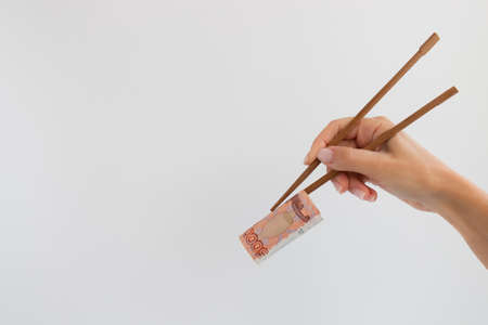 Roll from 5000 rubles in timber chopsticks on a white with a copy space.の写真素材