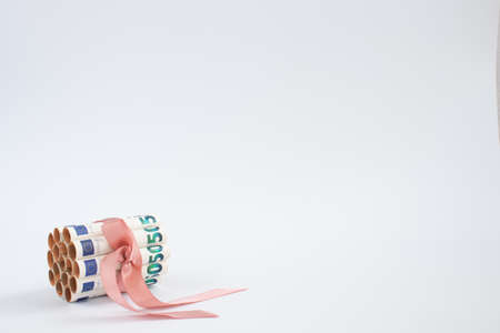 Banknotes of 50 euro in rolls, tied with pink gift ribbon on a white background.の写真素材