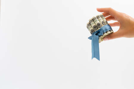 Female hand holding rolled 100 dollar bills tied with blue gift ribbon.の写真素材