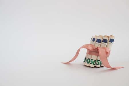 50 euro in rolls, tied with pink gift ribbon on a white with copy space.の写真素材