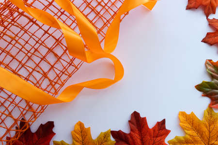 Autumn frame from maple leaves with orange decorative mesh and ribbon.の写真素材