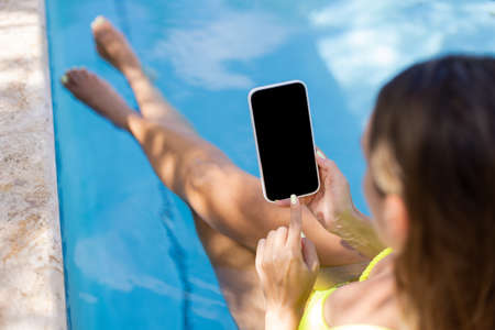 Girl relaxing in swimming pool with smartphone. Closeup. Selective focus