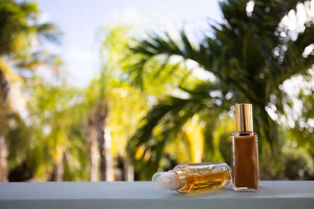Small bottles of cosmetic liquids on a palm leaves background. Selective focus.