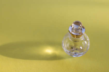 Small bottle of cosmetic liquid on a yellow background. Selective focus.