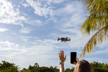 Girl giving stop signal with hand to flying drone and taking photo of it. Selective focus.の写真素材
