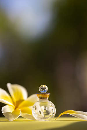Small bottle of perfume or essential oil with a tropical flower. Selective focus.