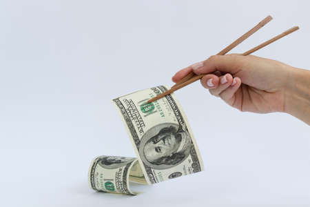 American dollars in a timber chopstick on a white background, closeup.の写真素材