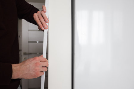 Man glues protective decorative plastic corner on the wall in apartment.の写真素材