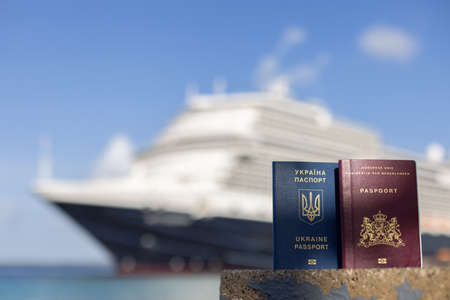 Female hand holding Ukrainian passport on the background of the sea.