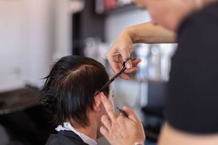 Cutting hair at hairdresser. Treat hair at beauty salon. Closeup. Selective focus