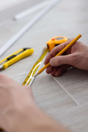 Man hands measuring decorative plastic corner. Repairing at home.