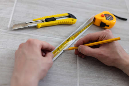 Man hands measuring decorative plastic corner. Repairing at home.の写真素材
