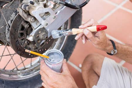 Man painting motorbike with brush at home. Renew old motorbike.の写真素材