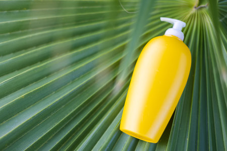 Yellow cosmetic bottle on the palm leaf closeup.