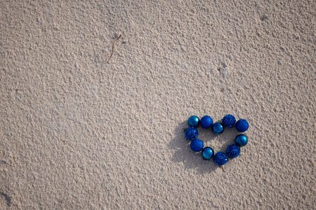 Heart from blue Christmas balls on the sandy beach. Top view.の写真素材
