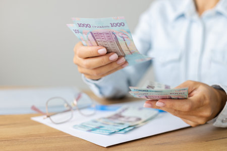 Woman holding Ukrainian 1000 bill banknotes. Count Ukrainian moneyの写真素材