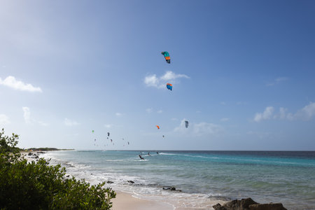 Sandy beach with turquoise water and kitesurfers on the horizon. Kitesurfing lessons.の写真素材