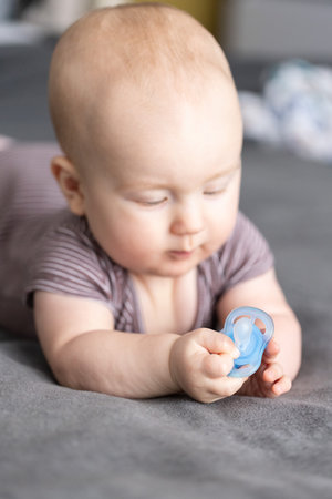 Baby looking with interest to the blue pacifier.