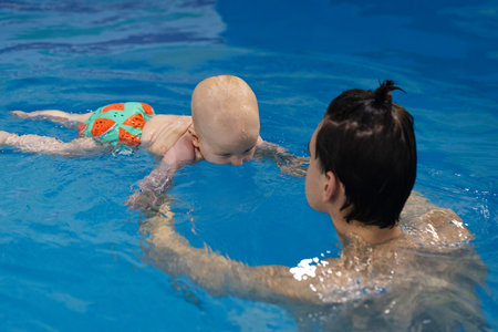 Baby trying to dive under water. Baby drinking water of swimming pool. Disinfection and cleaning of swimming pool.の写真素材