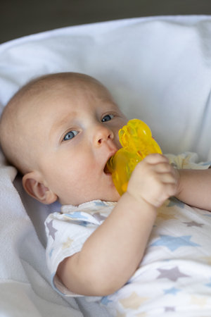 Newborn baby chewing on teething ring toy.