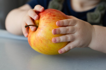 Little kids hands holding big ripe apple. Closeup.の写真素材