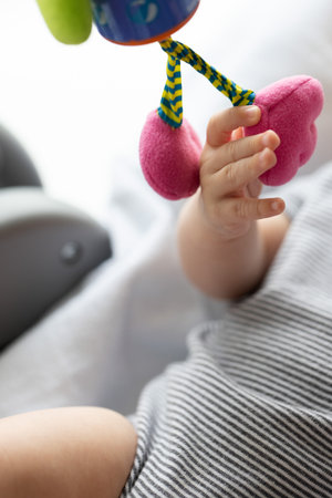 Newborn babys hand touching hanging toy. Fine motor skills concept. Closeup, selective focus.の写真素材