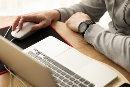 Man working behind a laptop wearing sport cozy clothing. Selective focus.の写真素材