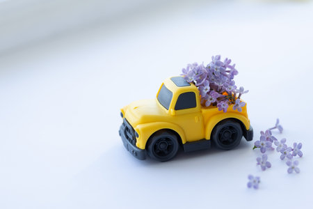 Yellow toy Picker delivering bouquet of lilac flowers. Closeup, selective focus.の写真素材