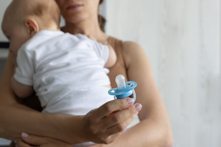 Mother holding little baby. Using pacifier concept. Closeup, selective focus.の写真素材
