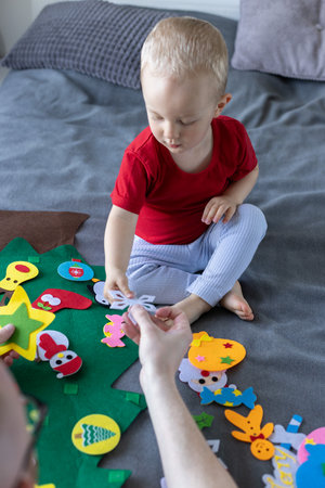 Father and his son decorating toy Christmas tree together. Educational games for children.の写真素材