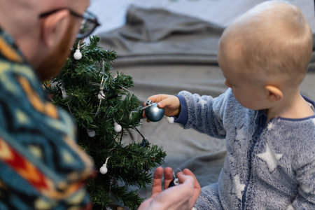 Little kid decorating Christmas tree together with his father.の写真素材