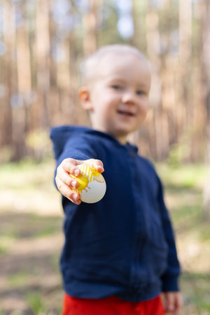 Smiling little boy giving Easter egg. Easter Sunday concept. Closeup, selective focus.の写真素材