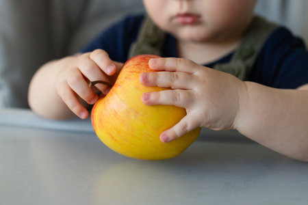 Little kids hands holding big ripe apple. Closeup.